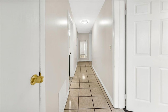 hallway featuring baseboards and light tile patterned flooring