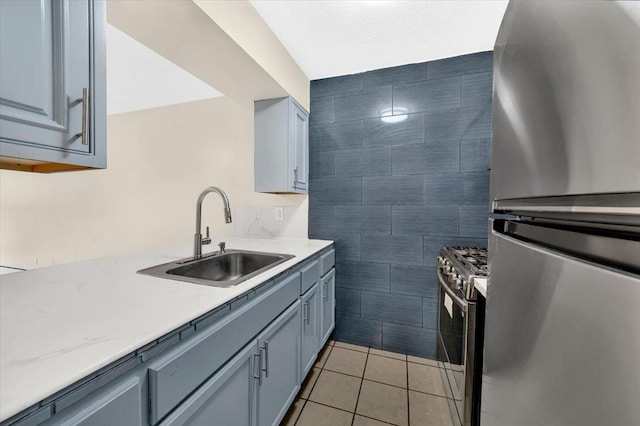 kitchen with a sink, stainless steel appliances, light tile patterned flooring, and gray cabinets