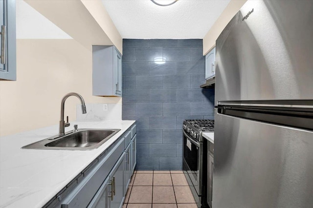 kitchen with light tile patterned floors, a sink, stainless steel appliances, tile walls, and light countertops