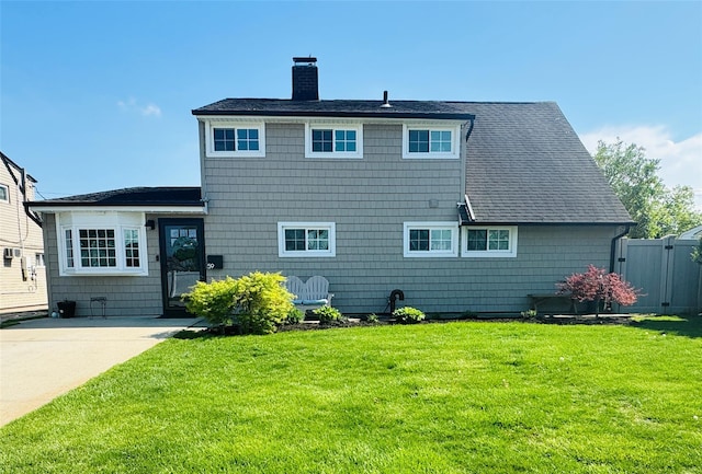 back of house featuring a chimney, a yard, and a shingled roof