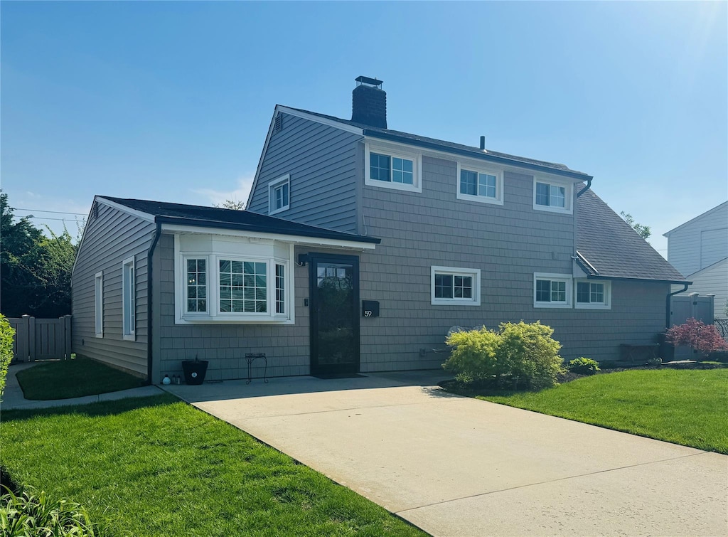 traditional home featuring a chimney, a patio area, a front lawn, and fence