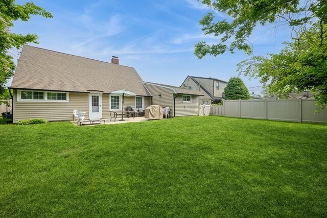 59 Springtime Ln S, Levittown, NY 11756 - rear view of house featuring a chimney, a patio, and roof with shingles