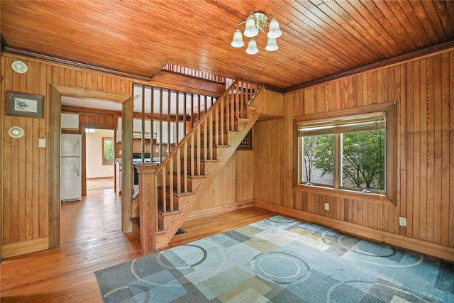 stairs featuring wooden ceiling, an inviting chandelier, wood walls, and baseboards