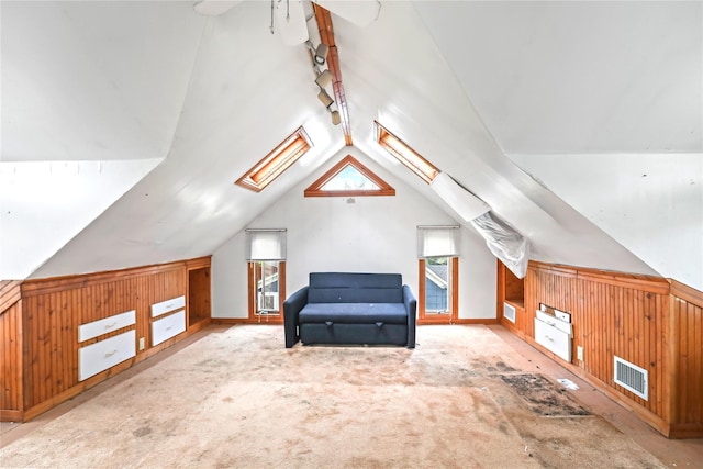 additional living space with wood walls, visible vents, and vaulted ceiling