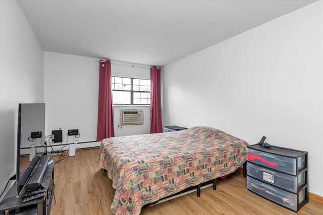 2-20 Capstan Ct Unit 102B, College Point, NY 11356 - bedroom featuring wood finished floors, a baseboard radiator, cooling unit, and an office area