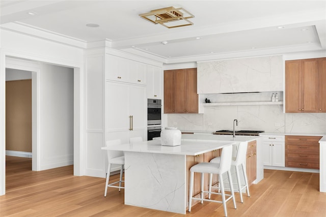 171 Oneck Ln, Westhampton Beach, NY 11978 - kitchen featuring a breakfast bar, light wood finished floors, backsplash, and an island with sink