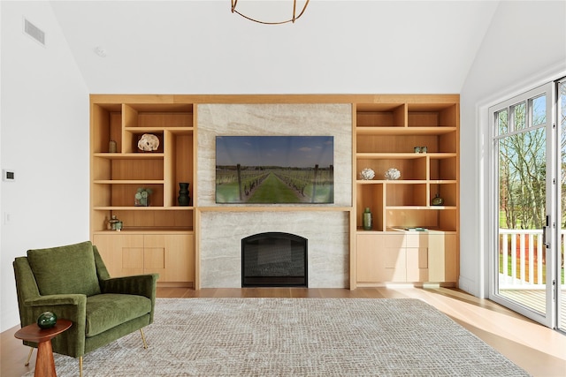 171 Oneck Ln, Westhampton Beach, NY 11978 - living room featuring visible vents, built in shelves, vaulted ceiling, a fireplace, and light wood-style flooring