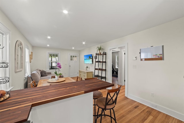 kitchen with wooden counters, light wood-type flooring, recessed lighting, baseboards, and a kitchen breakfast bar