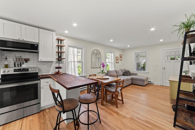 kitchen featuring stainless steel appliances, wooden counters, light wood-style floors, backsplash, and open shelves
