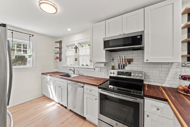 kitchen with wooden counters, open shelves, stainless steel appliances, a sink, and tasteful backsplash