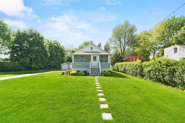 bungalow-style home with a front lawn, driveway, a sunroom, and a detached garage