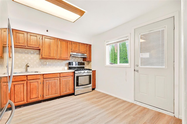 22 Chauncey St, Tuckahoe, NY 10707 - kitchen with stainless steel gas stove, a sink, light wood finished floors, tasteful backsplash, and under cabinet range hood