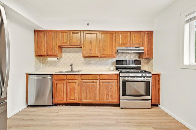 22 Chauncey St, Tuckahoe, NY 10707 - kitchen with appliances with stainless steel finishes, under cabinet range hood, a sink, decorative backsplash, and light wood-style flooring