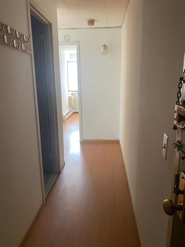 corridor with a baseboard radiator and light wood-style floors