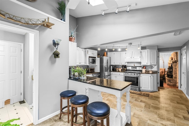 46 Quaker Hill Rd, Monroe, NY 10950 - kitchen featuring a peninsula, rail lighting, a breakfast bar area, white cabinets, and appliances with stainless steel finishes