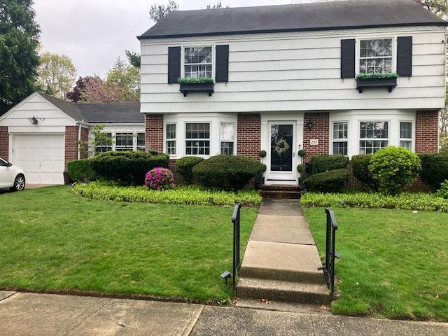 colonial house featuring a front lawn, brick siding, and an attached garage