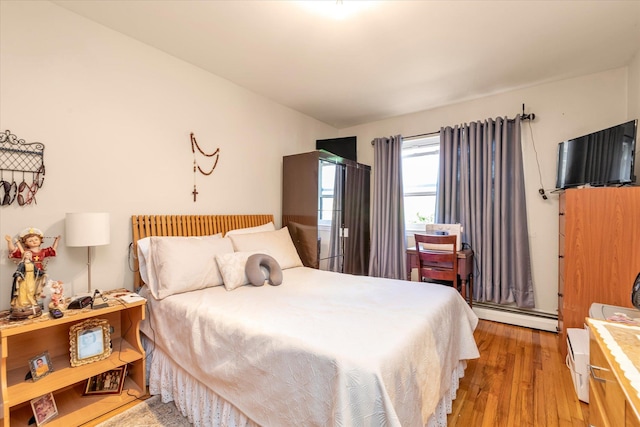 bedroom with light wood-type flooring and a baseboard heating unit
