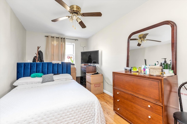 bedroom with light wood finished floors, baseboards, and ceiling fan