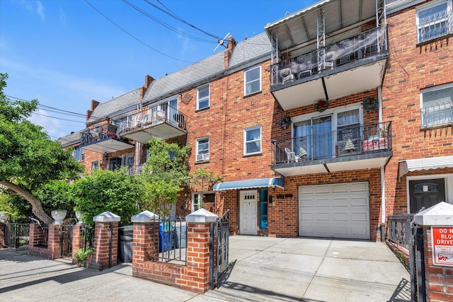 view of front of property with concrete driveway, a balcony, brick siding, and a garage