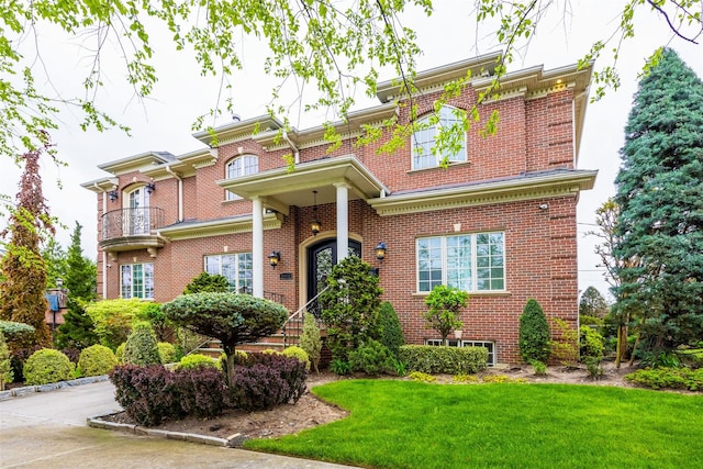 view of front of property with brick siding, a front yard, and a balcony