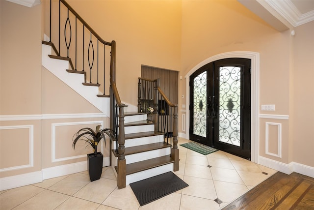 tiled entryway with french doors, stairway, arched walkways, baseboards, and ornamental molding