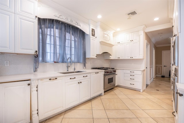 kitchen with high end stove, a sink, ornamental molding, white cabinets, and light tile patterned floors