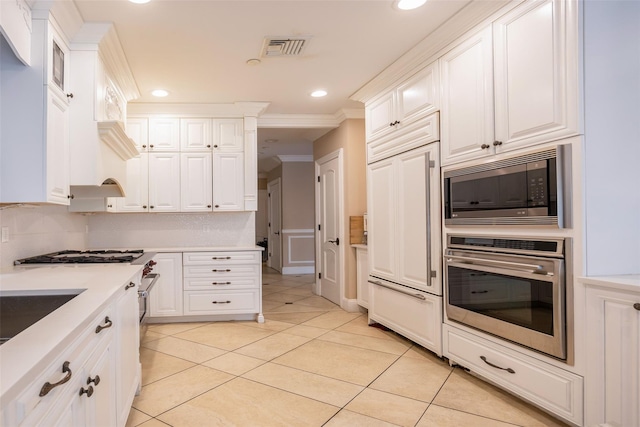 kitchen featuring built in appliances, ornamental molding, white cabinetry, light tile patterned floors, and light countertops