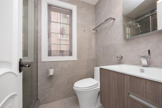 bathroom featuring tile walls, toilet, vanity, a walk in shower, and tile patterned floors
