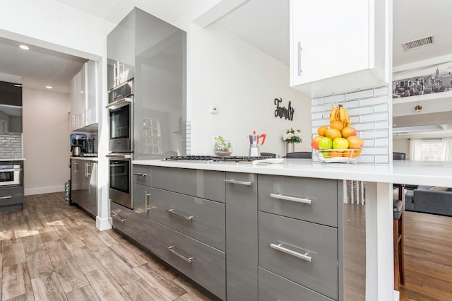 kitchen with gray cabinets, visible vents, light wood-style flooring, light countertops, and modern cabinets