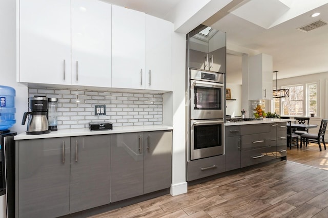 kitchen with gray cabinetry, appliances with stainless steel finishes, visible vents, and light countertops