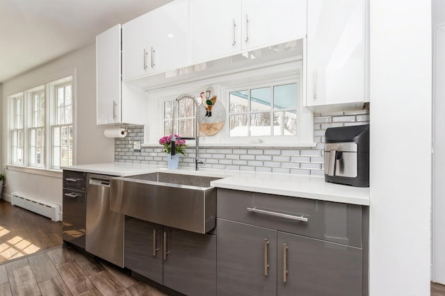 kitchen with dishwasher, light countertops, a baseboard radiator, and a sink