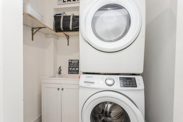 clothes washing area featuring stacked washer and dryer, a sink, and cabinet space