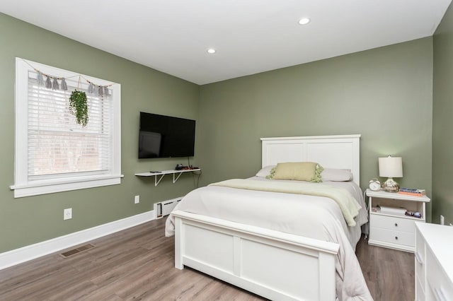 bedroom with recessed lighting, baseboards, a baseboard heating unit, visible vents, and wood finished floors