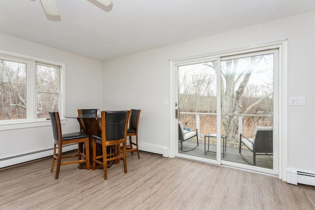 dining space featuring a ceiling fan, a baseboard radiator, baseboards, and wood finished floors