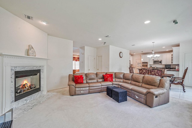 living area with light carpet, recessed lighting, a high end fireplace, and a chandelier