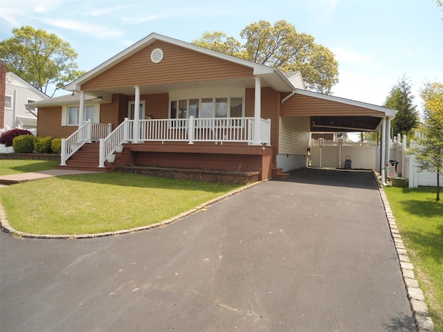 212 Wensley Ln, East Islip, NY 11730 - view of front of home with covered porch, asphalt driveway, a front lawn, and an attached carport