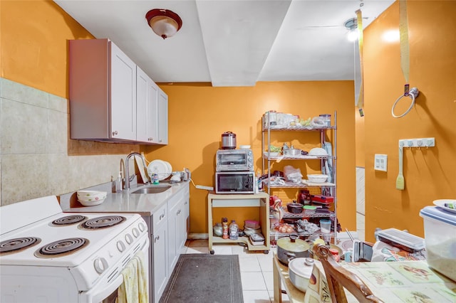 1934 Chatterton Ave, Bronx, NY 10472 - kitchen with white range with electric stovetop, a sink, light tile patterned floors, white cabinetry, and light countertops