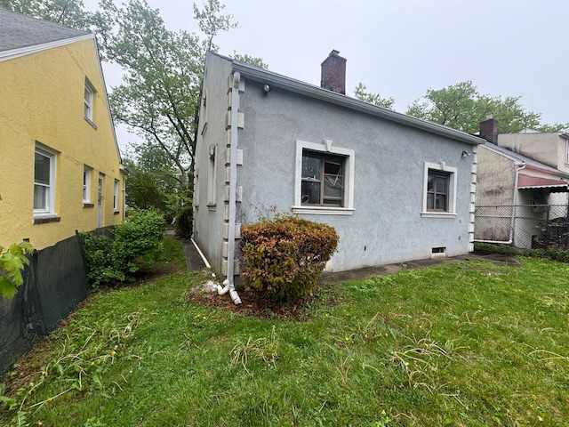 548 S 10th Ave, Mount Vernon, NY 10550 - back of house with stucco siding, a chimney, fence, and a lawn