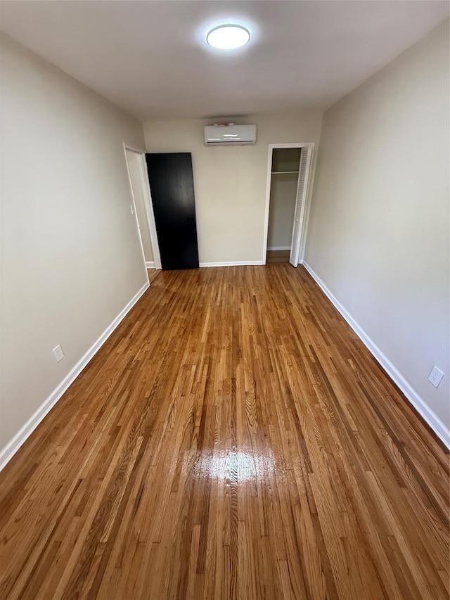 3106 Eastchester Rd, Bronx, NY 10469 - unfurnished bedroom featuring baseboards, a closet, a wall unit AC, and wood finished floors