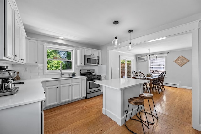 32 Lafayette Ave, Beacon, NY 12508 - kitchen featuring stainless steel appliances, a kitchen breakfast bar, decorative backsplash, and light wood finished floors
