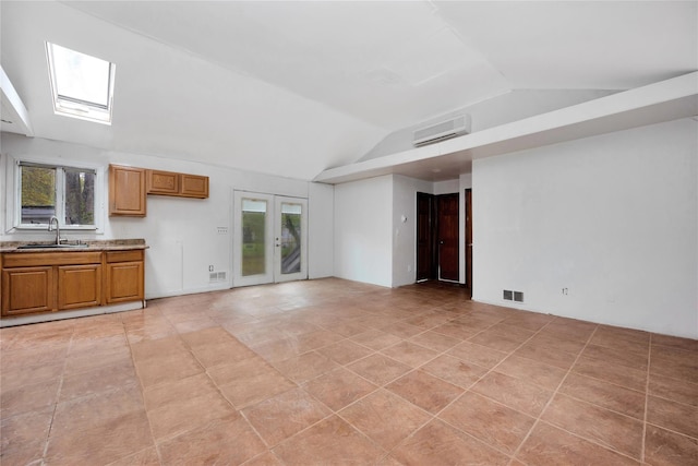 unfurnished living room featuring a sink, lofted ceiling, french doors, light tile patterned floors, and a skylight