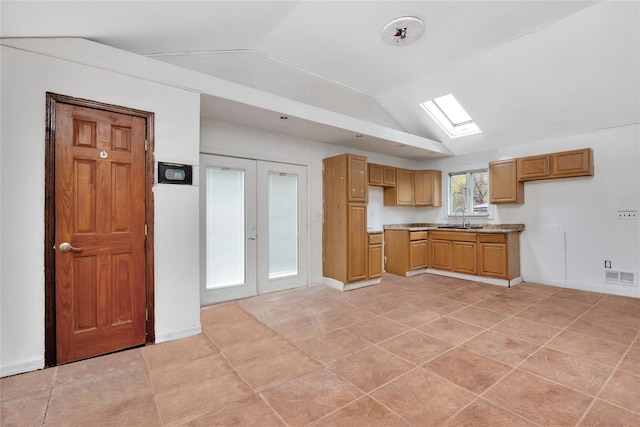 kitchen with a sink, lofted ceiling, french doors, light countertops, and a skylight