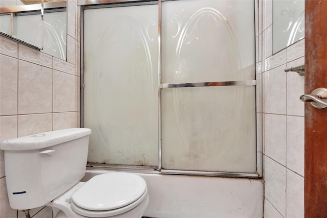 full bath featuring tile walls, toilet, and bath / shower combo with glass door
