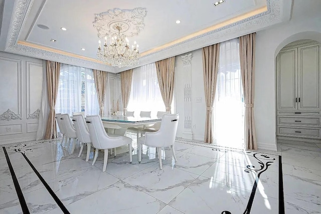 dining room featuring a tray ceiling, recessed lighting, marble finish floor, an inviting chandelier, and arched walkways
