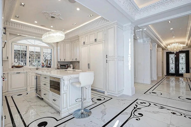 kitchen featuring an inviting chandelier, a raised ceiling, a kitchen island, marble finish floor, and wine cooler