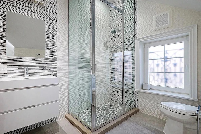 full bathroom featuring toilet, tile walls, visible vents, tile patterned floors, and a stall shower