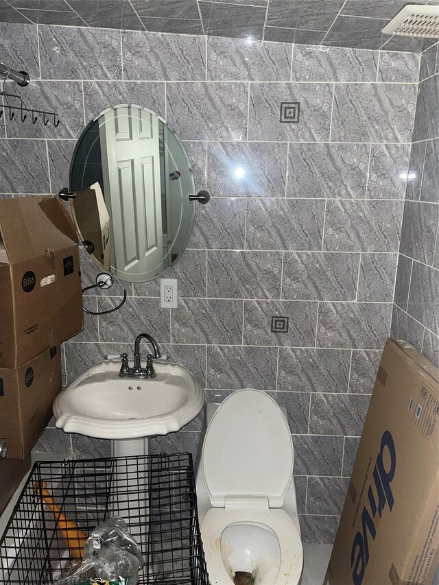 half bath with tile walls and a sink