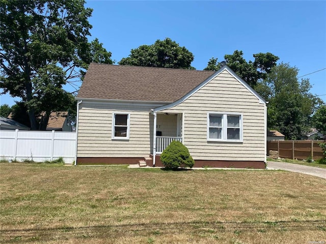bungalow with a front yard, roof with shingles, and fence