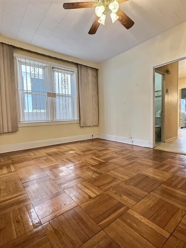 empty room featuring ceiling fan and baseboards