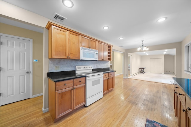kitchen featuring white appliances, visible vents, an inviting chandelier, baseboards, and dark countertops